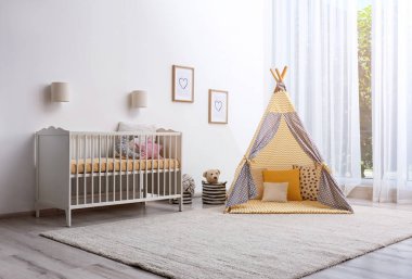 Oyun çadırı ve oyuncaklarla dolu bir bebek odası.