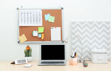 Çalışma alanı ile mantar pano ve masa üstünde laptop