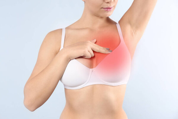 Woman doing breast self-examination on light background. Cancer awareness