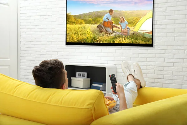 Молодий Чоловік Дивиться Телевізор Їсть Фішки Дивані Вдома — стокове фото