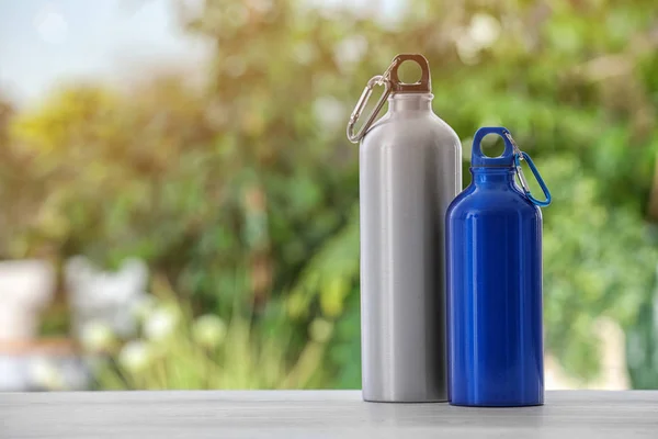 Sports water bottles on table against blurred background. Space for text