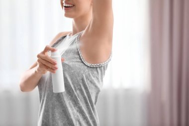 Güzel genç kadın odada deodorant uygulamak