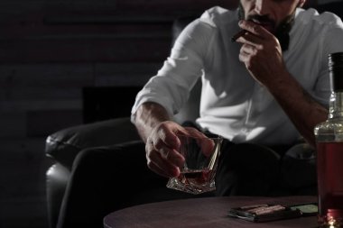Bardak viski ve puro kapalı masada oturan adam