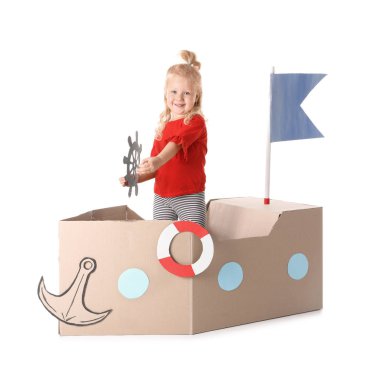 Sevimli küçük kız beyaz zemin üzerine karton gemi ile oynarken