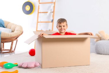 Sevimli küçük çocuk evde karton kutu ile oynamak