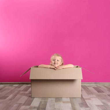 Sevimli küçük kız renk duvarının yakınında karton kutu ile oynarken