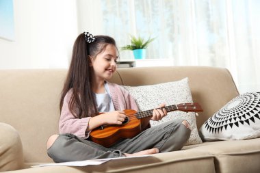 Sevimli küçük kız odasında kanepede gitar çalmak
