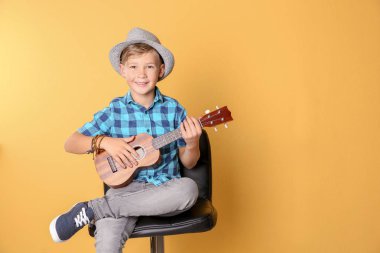 Sandalyede oturan ve renkli arka planı gitar çalmak küçük çocuk. Metin için yer