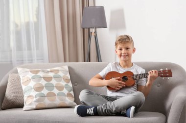 Küçük çocuk odasında kanepede gitar çalmak. Metin için yer