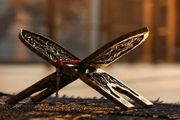 Rehal with prayer beads on Muslim prayer mat indoors