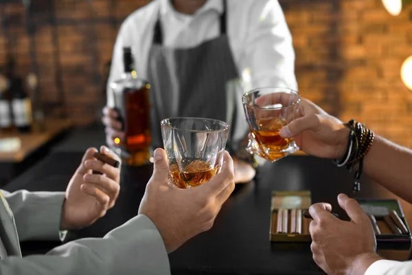 Friends drinking whiskey together in bar, closeup