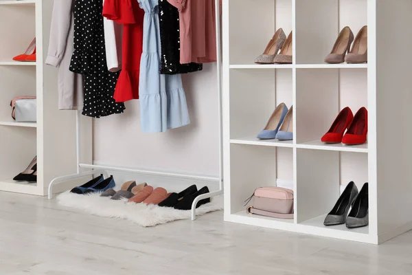 Wardrobe shelves with different stylish shoes and clothes indoors. Idea for interior design