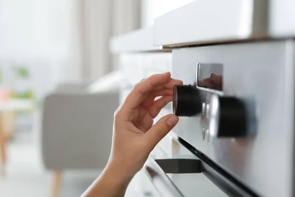 Woman regulating cooking mode on oven panel, closeup