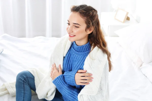 美丽的少女在温暖舒适的毛衣与格子坐在家里的床上 — 图库照片