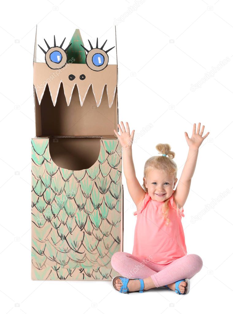 Cute little girl playing with cardboard dragon on white background