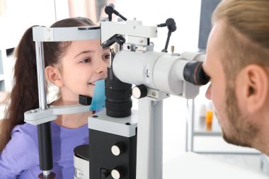 Çocuk Kliniği oftalmik ekipmanları ile inceleyerek küçük kız doktor