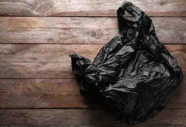 Ahşap arka plan üzerine açık tek kullanımlık plastik torba. Metin için yer
