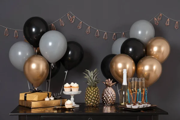 Party treats and items on table in room decorated with balloons