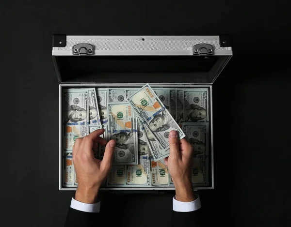 Üzletember Számít Pénz Több Mint Bőröndöt Sötét Háttér Felülnézet — Stock Fotó