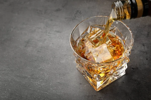 テーブルの上の氷とグラスにボトルからウイスキーを注ぐ テキストのためのスペース — ストック写真