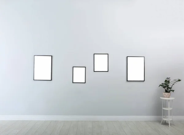 Frames with empty canvases on wall in modern art gallery. Mockup for design