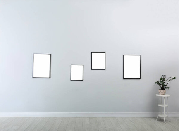 Frames with empty canvases on wall in modern art gallery. Mockup for design