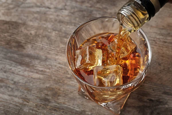 テーブル クローズ アップに氷でガラスのボトルからウイスキーを注ぐ — ストック写真
