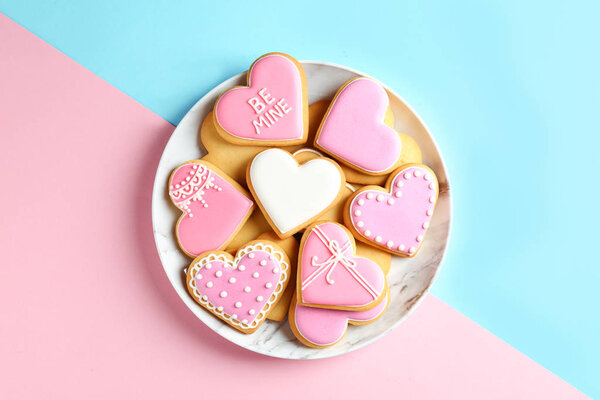 Plate with decorated heart shaped cookies on color background, top view