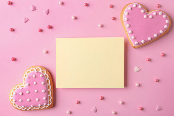 Flat lay composition with heart shaped cookies and blank card on color background, space for text