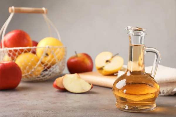 Composition with jug of apple vinegar on table. Space for text