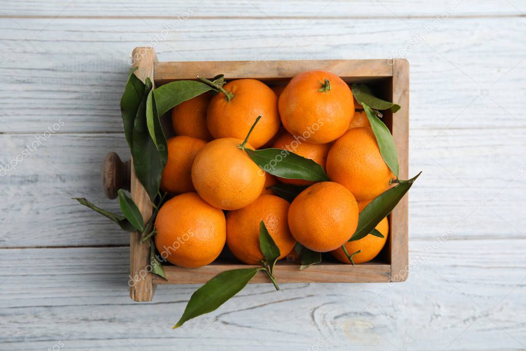 Crate with fresh ripe tangerines on wooden background, top view