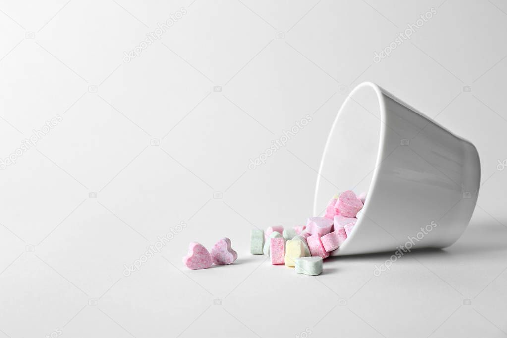 Small heart shaped candies and bowl on white background. Space for text