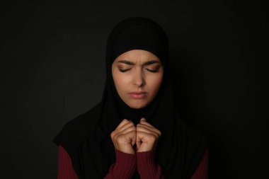 Koyu arka plan üzerinde dua hijab üzgün Müslüman kadın portresi