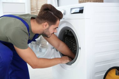Genç tamirci evde çamaşır makinesi tamir. Çamaşır günü