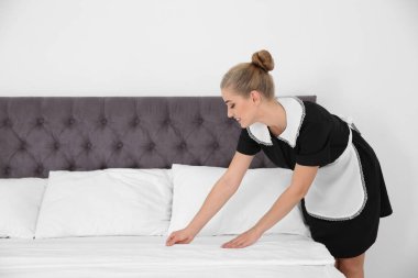 Otel odasında yatak yapma genç Oda hizmetçisi