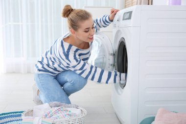 Evde çamaşır makinesi kullanan genç kadın. Çamaşır günü