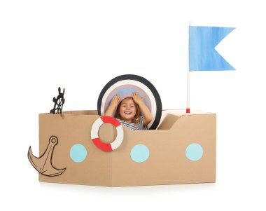 Sevimli küçük kız beyaz zemin üzerine karton gemi ile oynarken