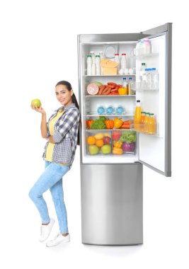 Beyaz arka plan üzerine açık buzdolabı yakınındaki apple ile genç kadın