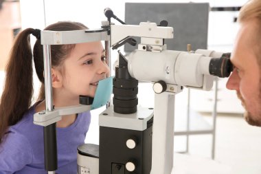 Çocuk Kliniği oftalmik ekipmanları ile inceleyerek küçük kız doktor