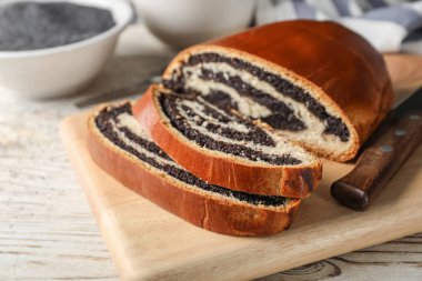 Haşhaş tohumu ile lezzetli tatlı çörek ahşap masanın üstüne kesmek