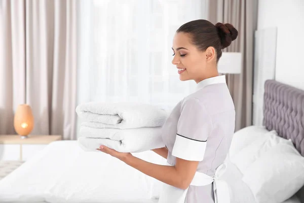 年轻的女服务员与干净的毛巾在卧室 — 图库照片