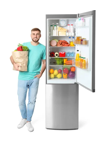 Jeune Homme Avec Sac Épicerie Près Réfrigérateur Ouvert Sur Fond — Photo