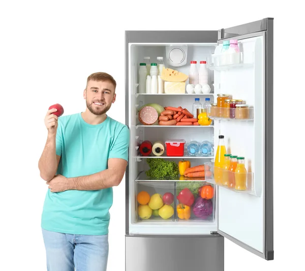 Hombre Joven Con Manzana Cerca Refrigerador Abierto Sobre Fondo Blanco — Foto de Stock