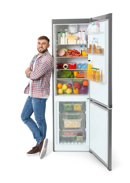 白い背景の上のオープン冷蔵庫近くに若い男 — ストック写真