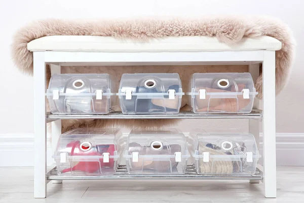 Plastic boxes with female shoes on rack near wall. Storage organization