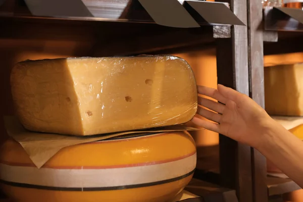 Woman choosing tasty cheese from display in store