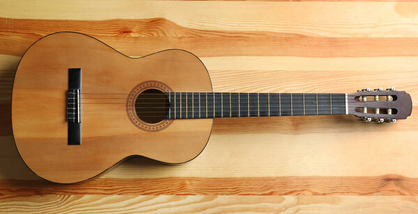 Beautiful classical guitar on wooden background, top view