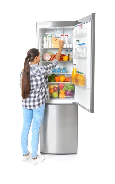 白い背景の上の冷蔵庫からチーズを取る若い女性 — ストック写真