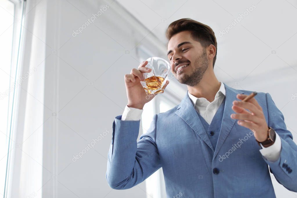 Man with glass of whiskey and cigar indoors