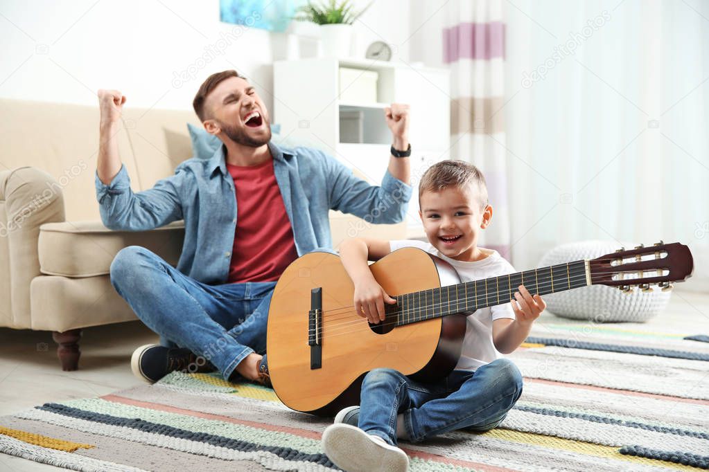 Father and son playing guitar and singing at home